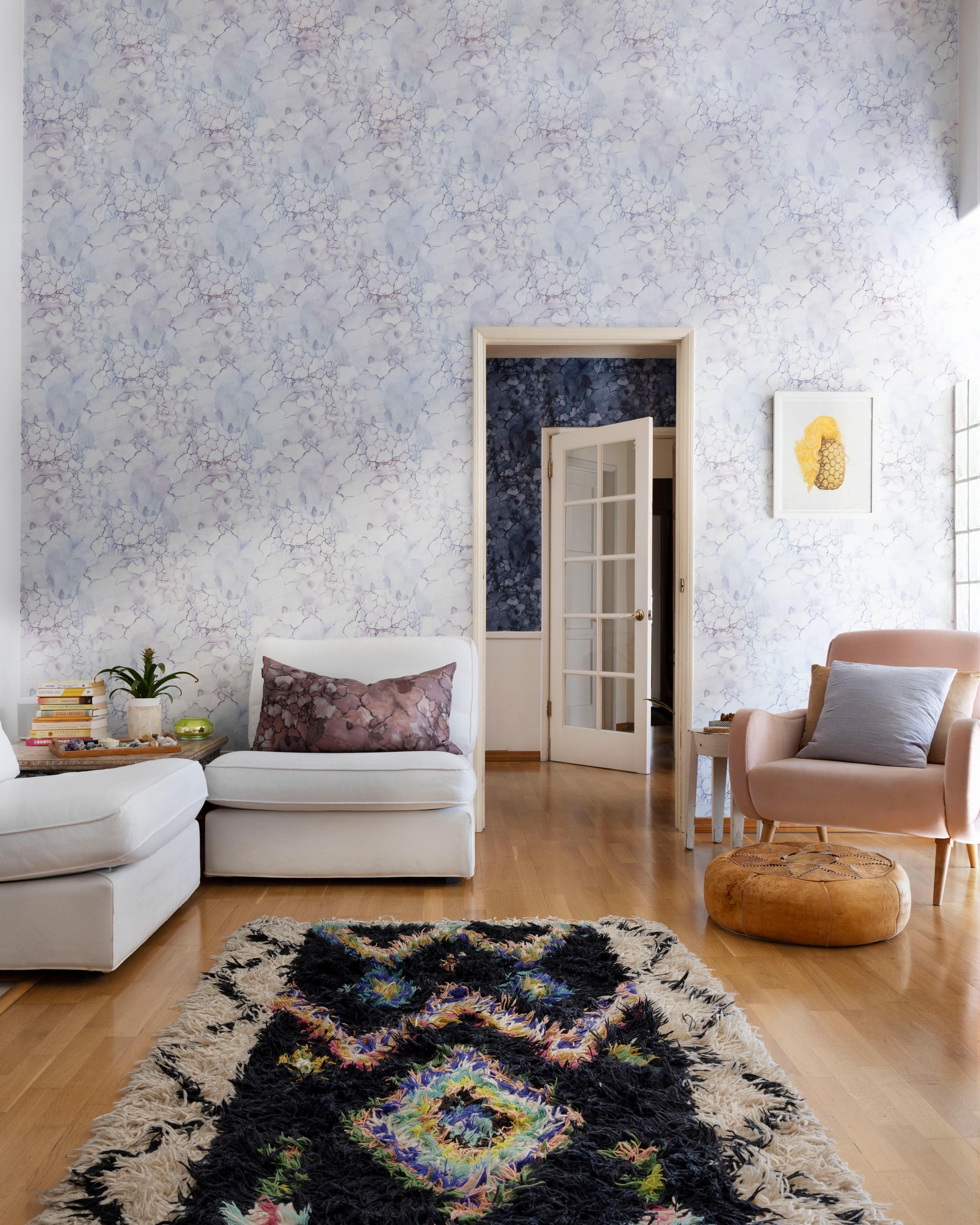 A maximalist living room tableau with walls papered in an abstract textural print in white, purple and gray.