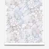 Partially unrolled wallpaper yardage in an abstract textural print in shades of white, purple and gray.