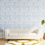 Styled living room tableau with a wall papered in an organic textural print in light blue on a white field.