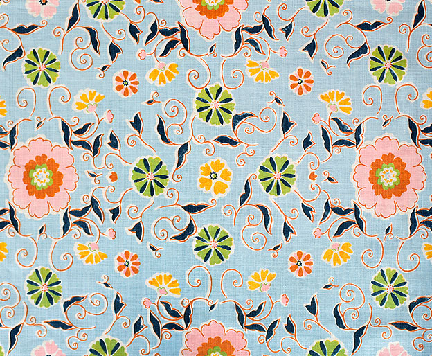 Detail of fabric in a playful floral print in pink, green and yellow on a light blue field.