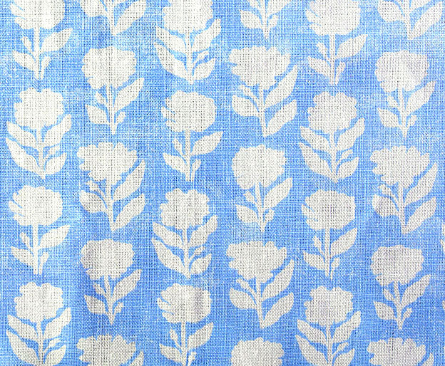 Detail of fabric in a classic floral silhouette print in cream on a light blue field