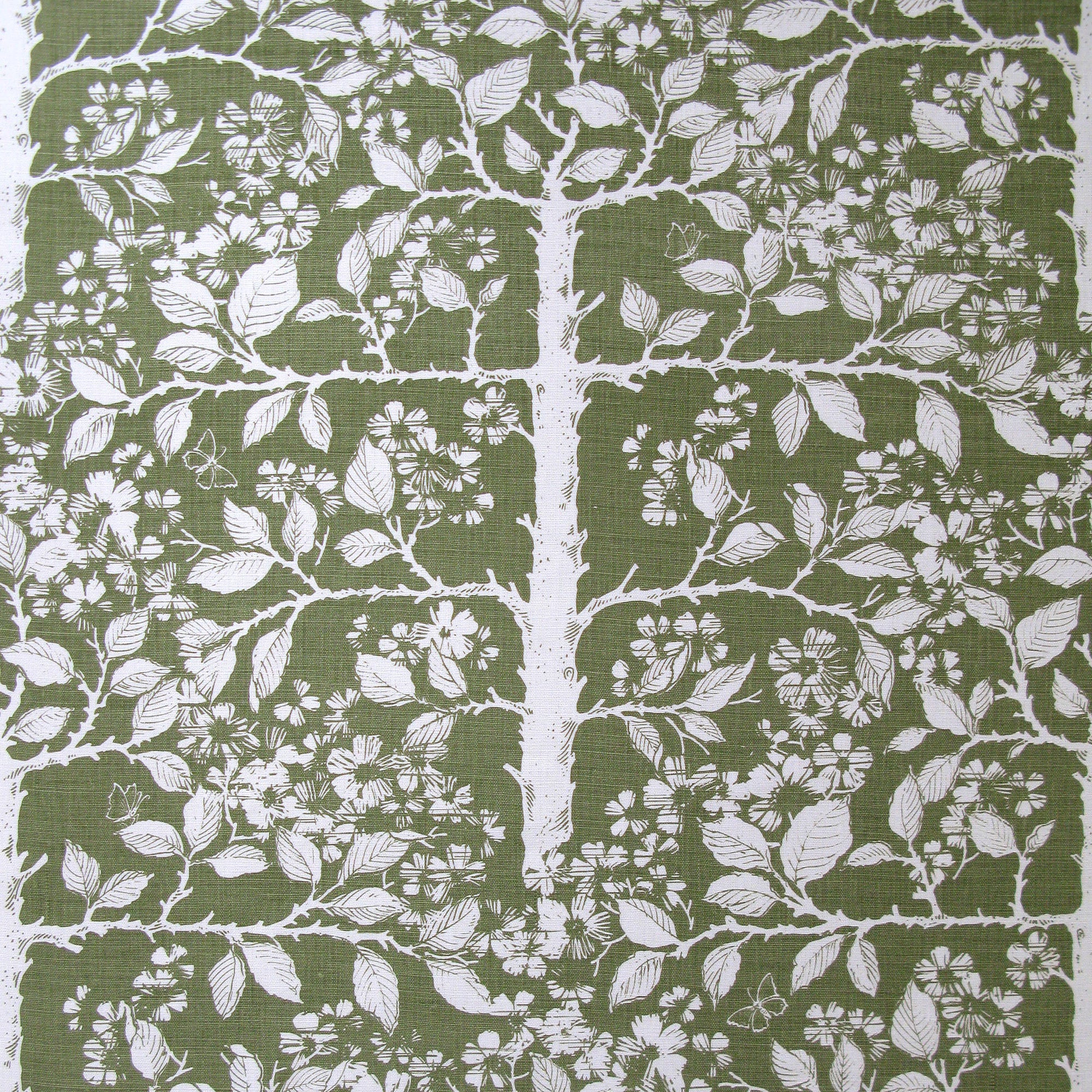 Detail of fabric in a large-scale tree and leaf print in white on a green field.