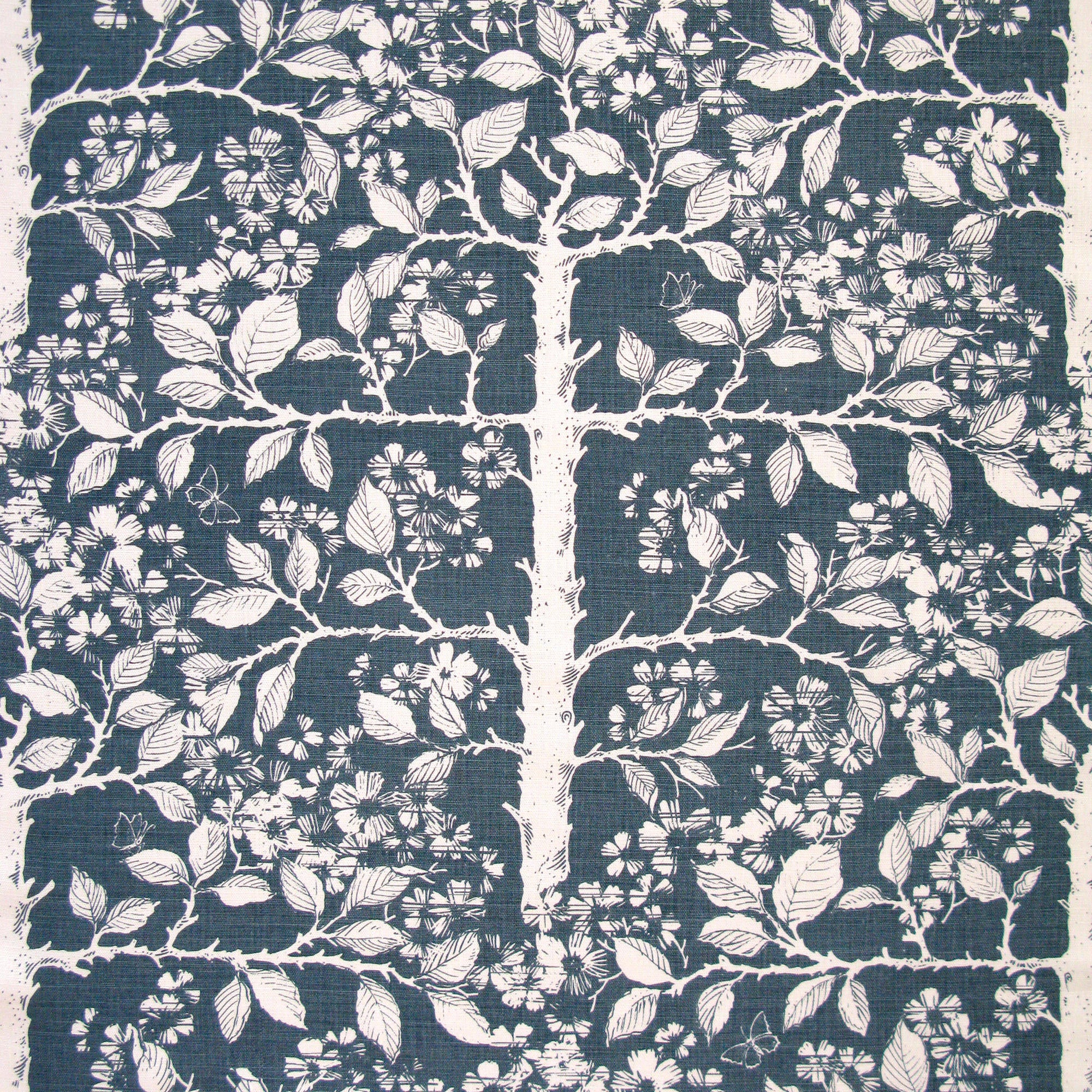 Detail of fabric in a large-scale tree and leaf print in cream on a navy field.