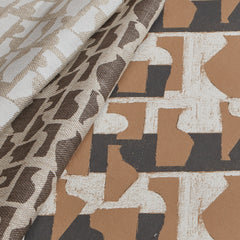 Overlapping sheets of wallpaper with block-printed shapes in shades of black, cream, tan and brown.