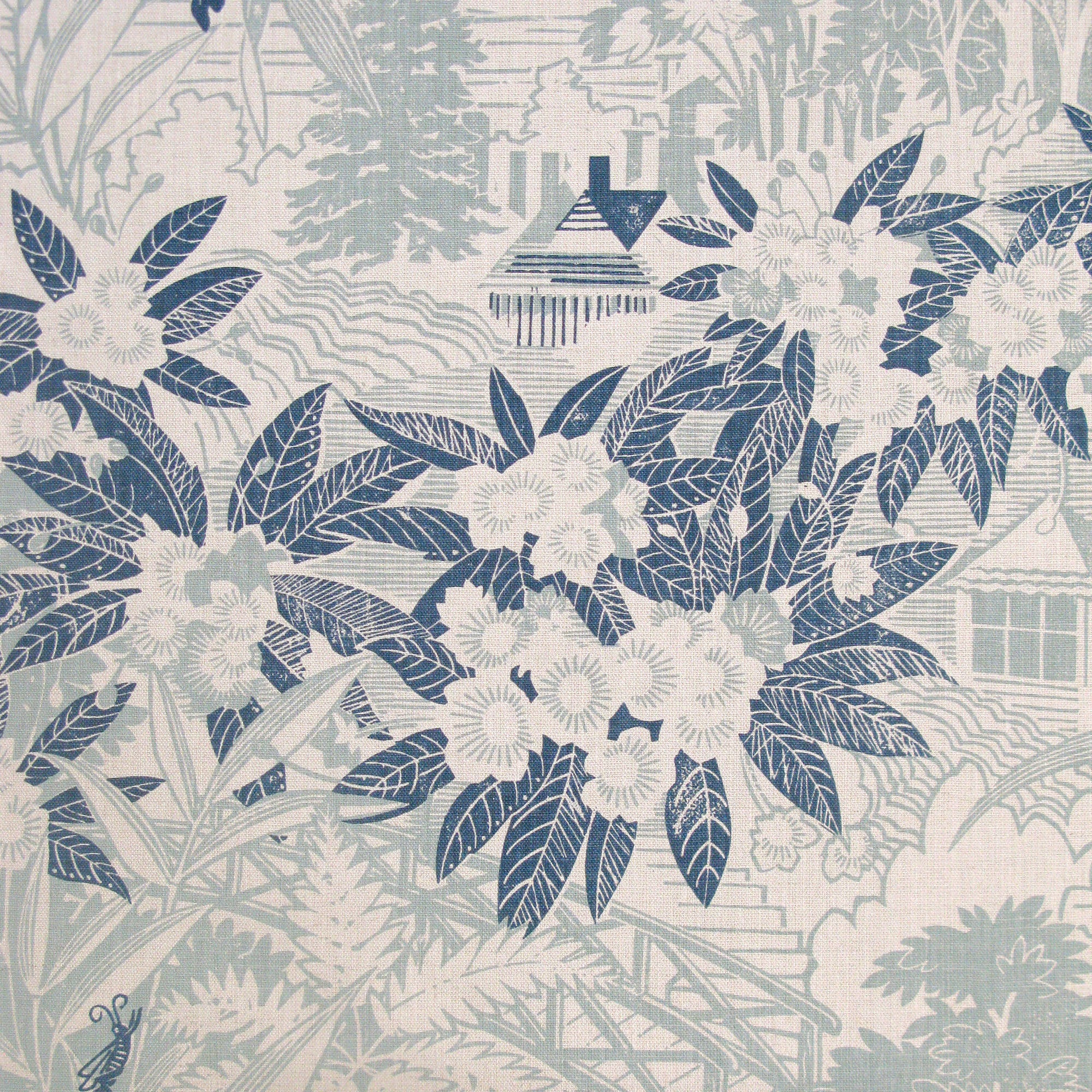 Detail of fabric in an intricate botanical, bridge and house print in navy and blue-gray on a cream field.