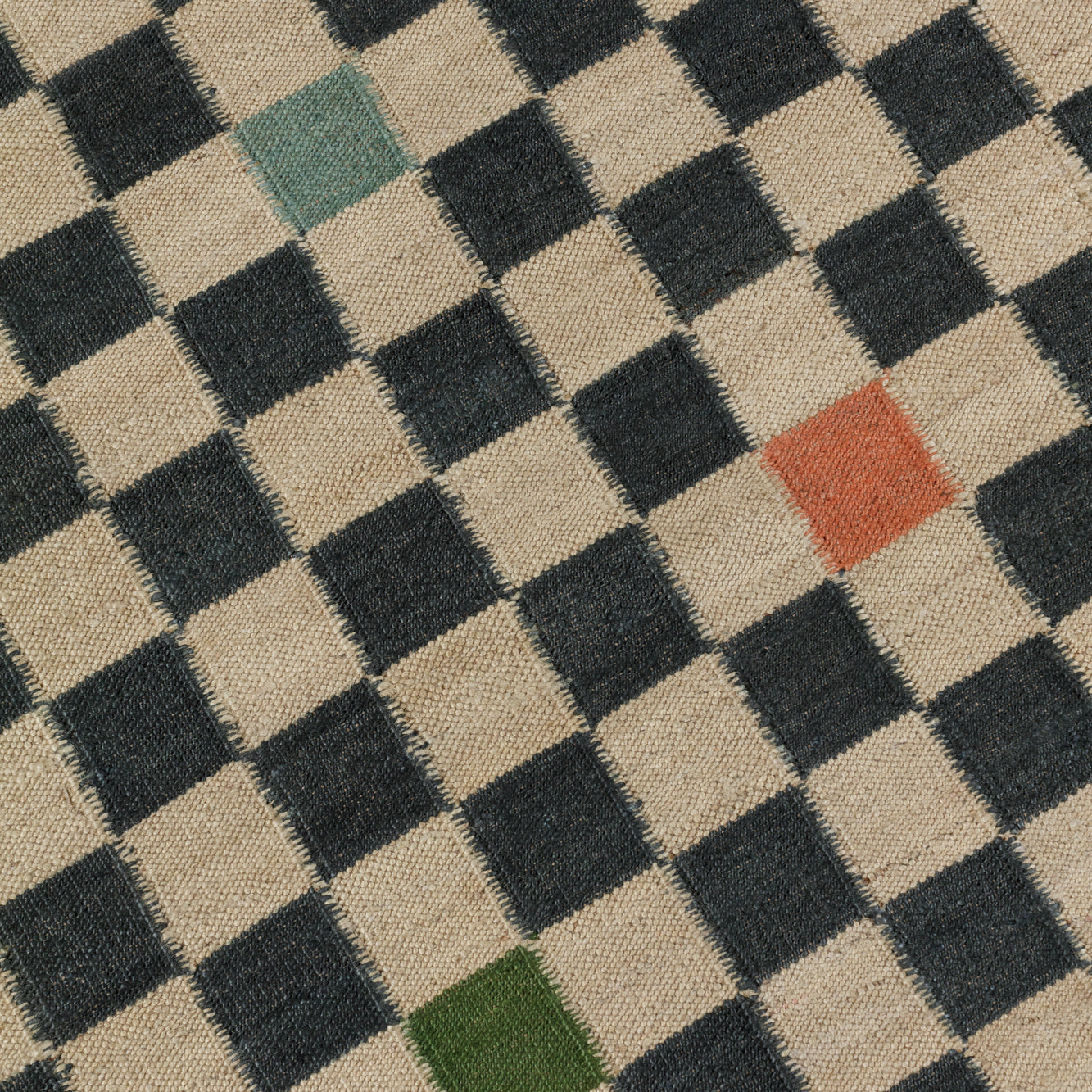 Detail of the Checkerboard Rug in King, a black and tan checkered pattern with random accents of green, sky blue and coral orange.