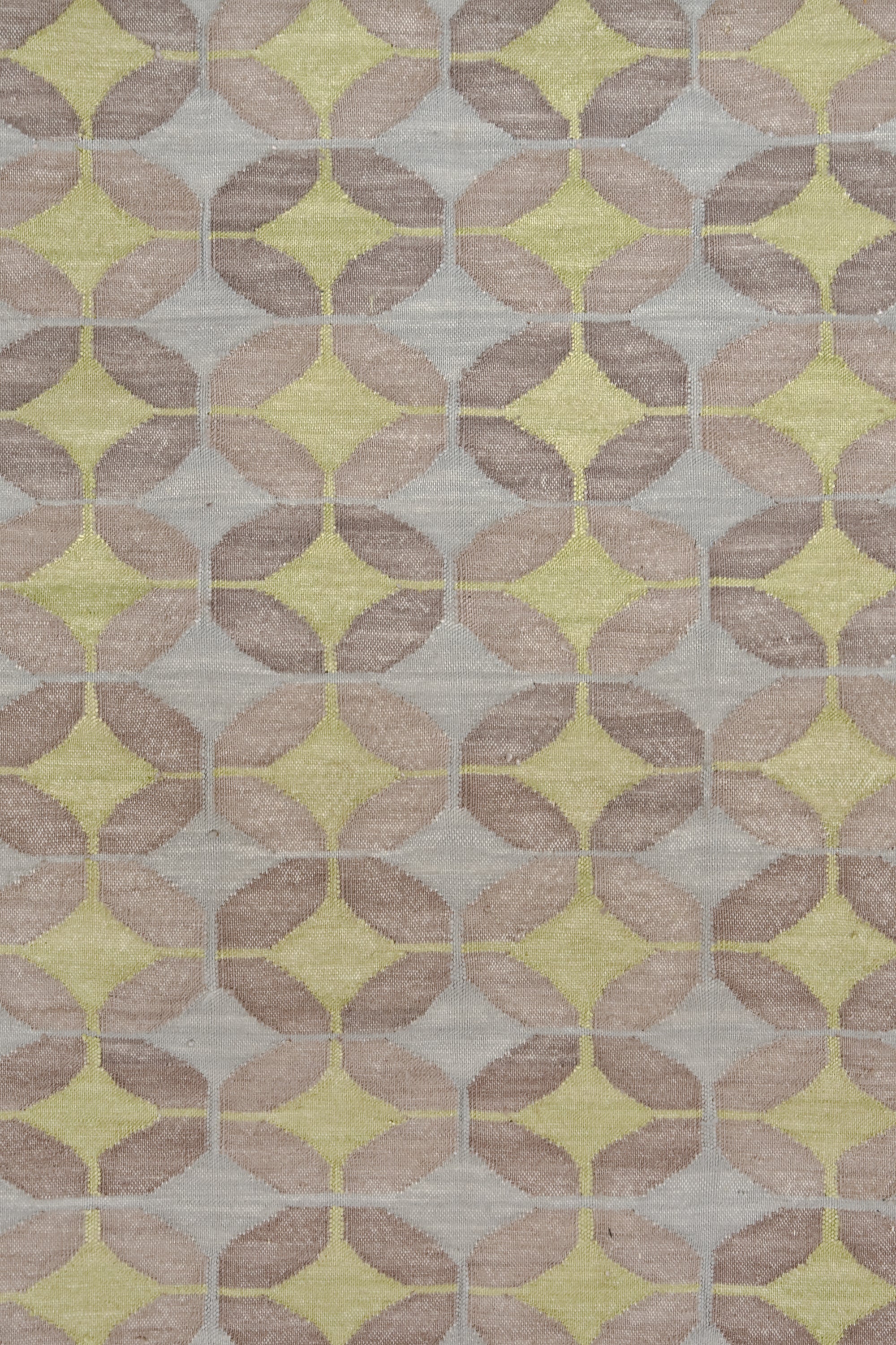 Petite Alhambra Rug featuring a pattern of linked circles that create a star like lattice in yellow and pale blue on a taupe field. 