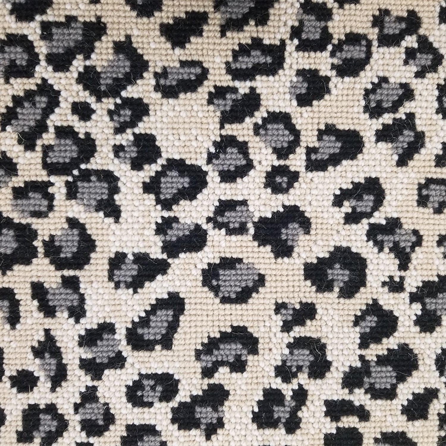 Wool broadloom carpet swatch in a leopard print in gray and black on a mottled cream field.