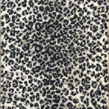 Wool broadloom carpet swatch in a cheetah print in black and tan on a cream field.