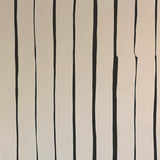 Detail of wallpaper in a playful irregular stripe print in black on a cream field.