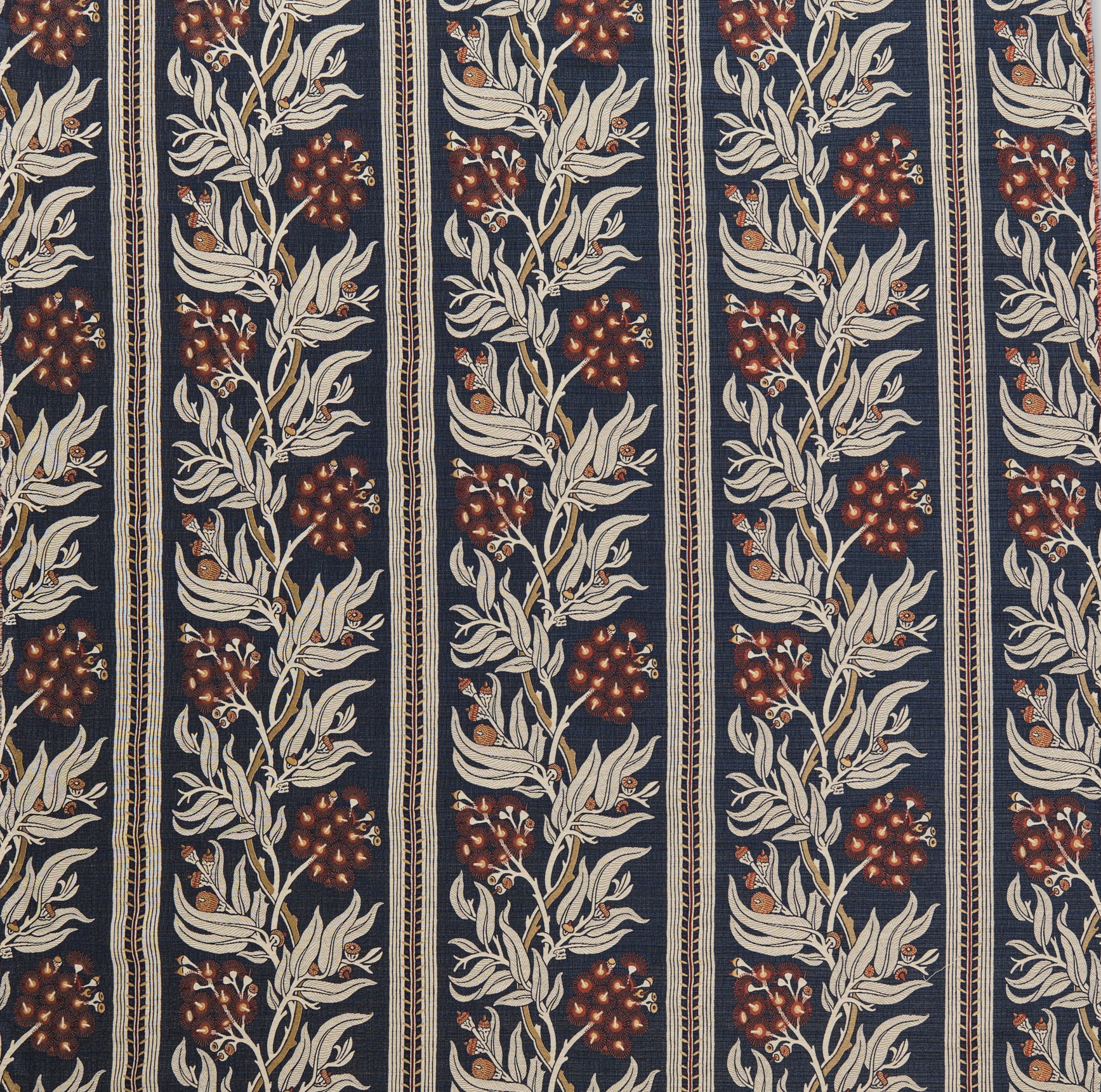 Woven performance fabric in a botanical branch and stripe design in beige, tan and red on a navy blue field. 