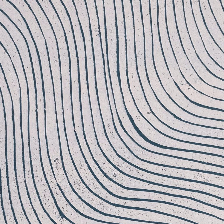 Detail of wallpaper in a curved linear print in navy on a mottled white field.