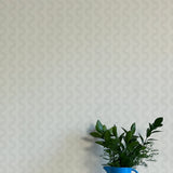 A vase of flowers stands in front of a wall papered in a playful curvy stripe print in gray on a light gray field.