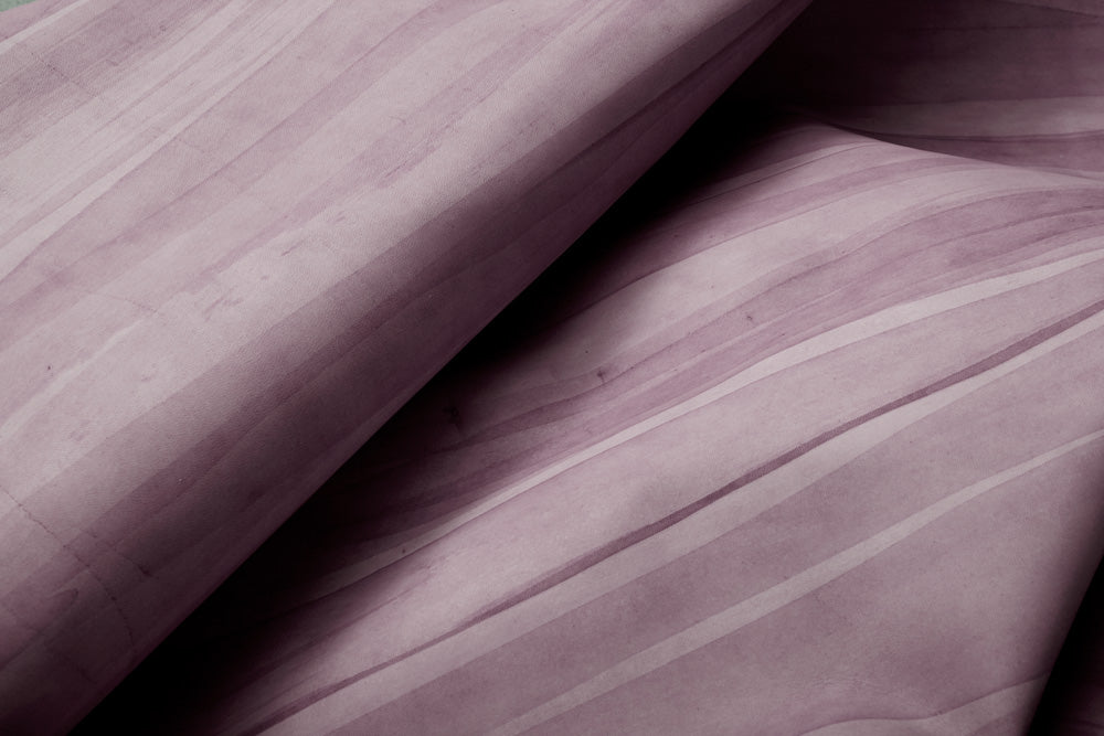 Draped cowhide rug in purple with an abstract stripe overlay in shades of purple and cream.