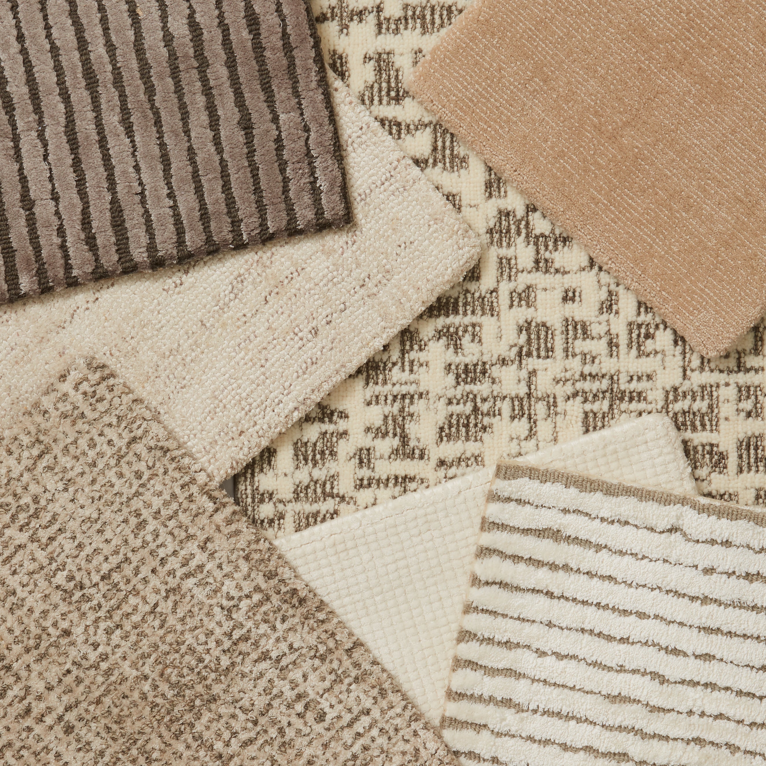 An array of broadloom carpet samples, in textural patterns in a range of neutral cream, taupe and tan. 