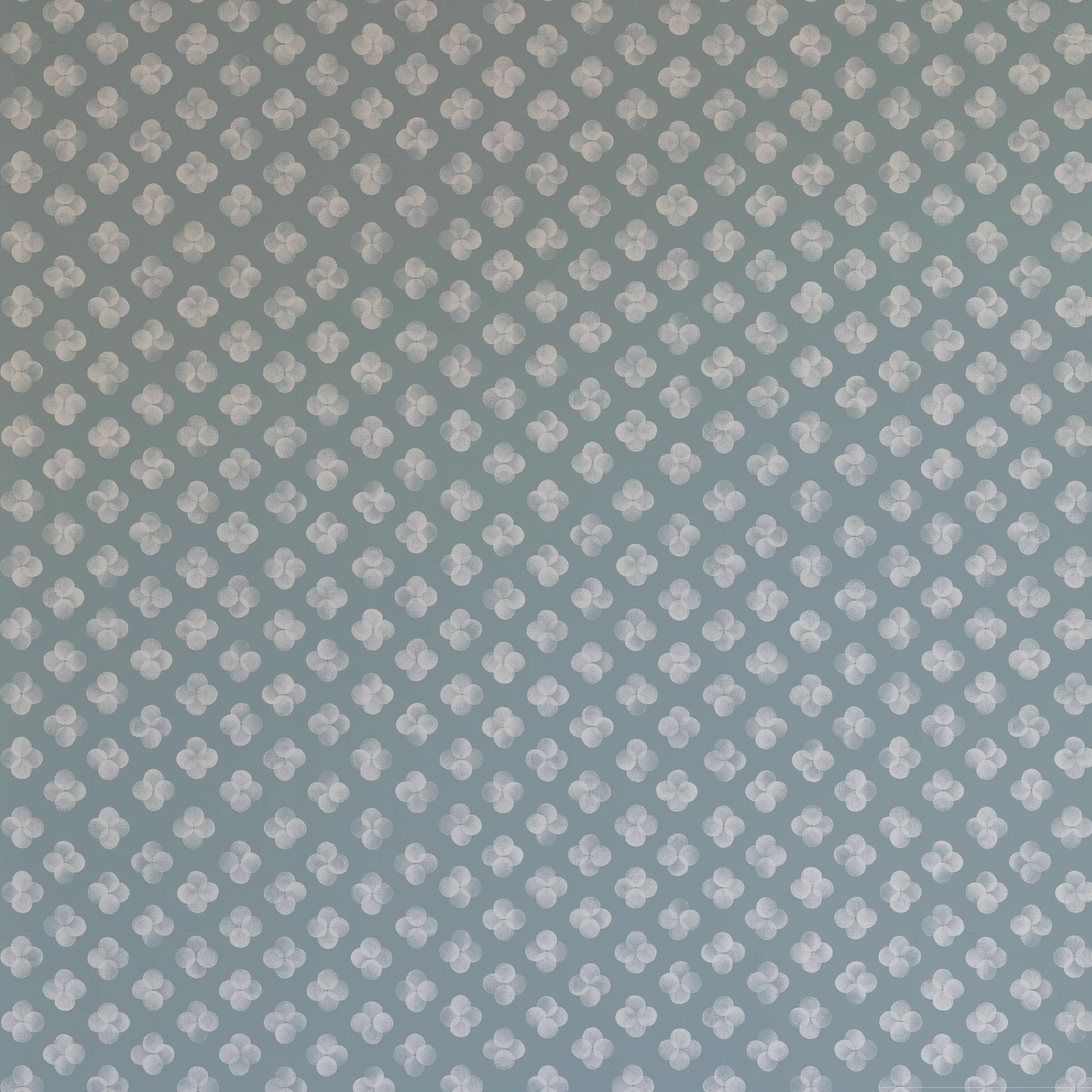 Detail of wallpaper in a minimalist quatrefoil pattern in gray on a blue field.