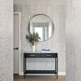 A hallway with a modernist end table and mirror and walls papered in an abstract textural pattern in metallic gray.