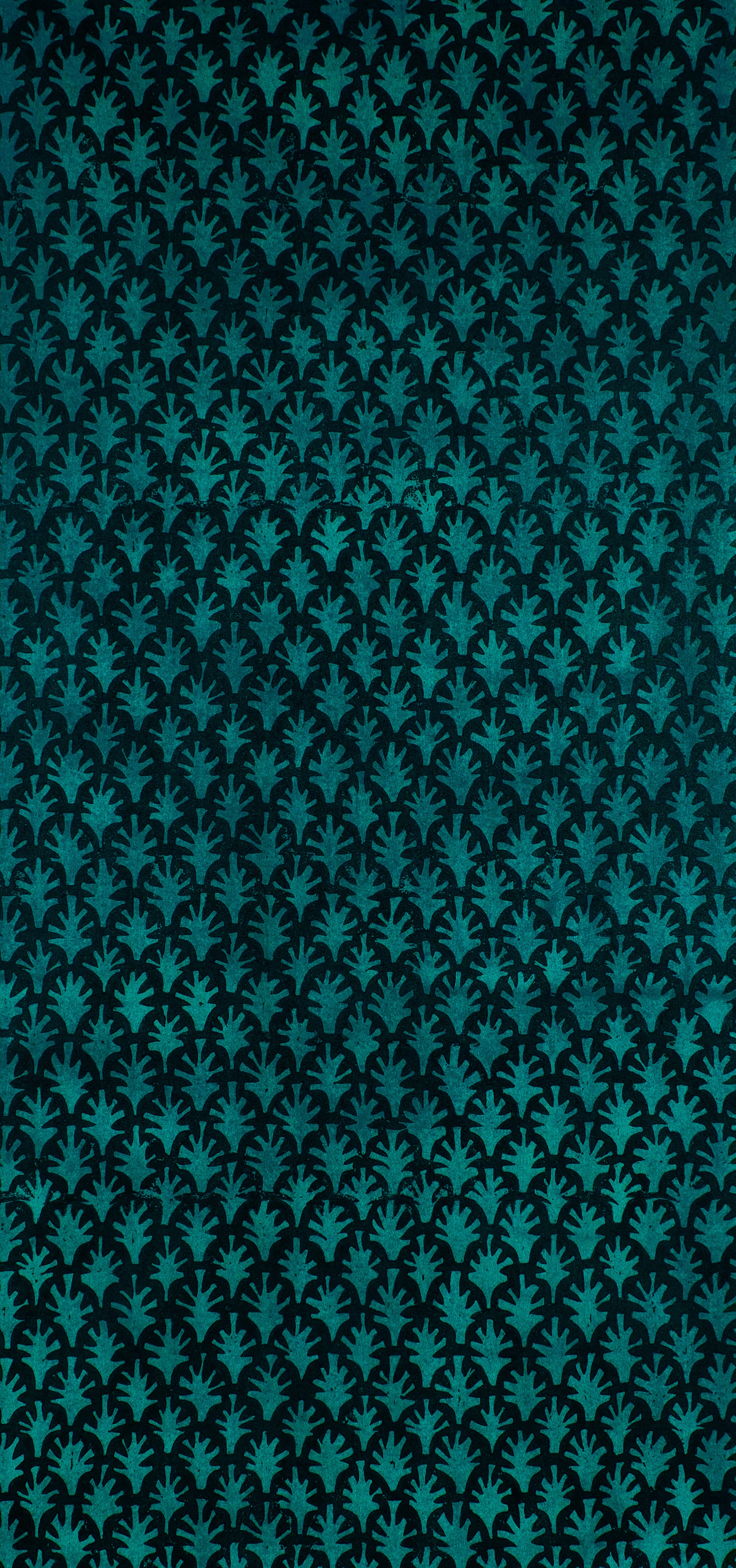 Detail of wallpaper in a repeating botanical grid print in turquoise on a black field.