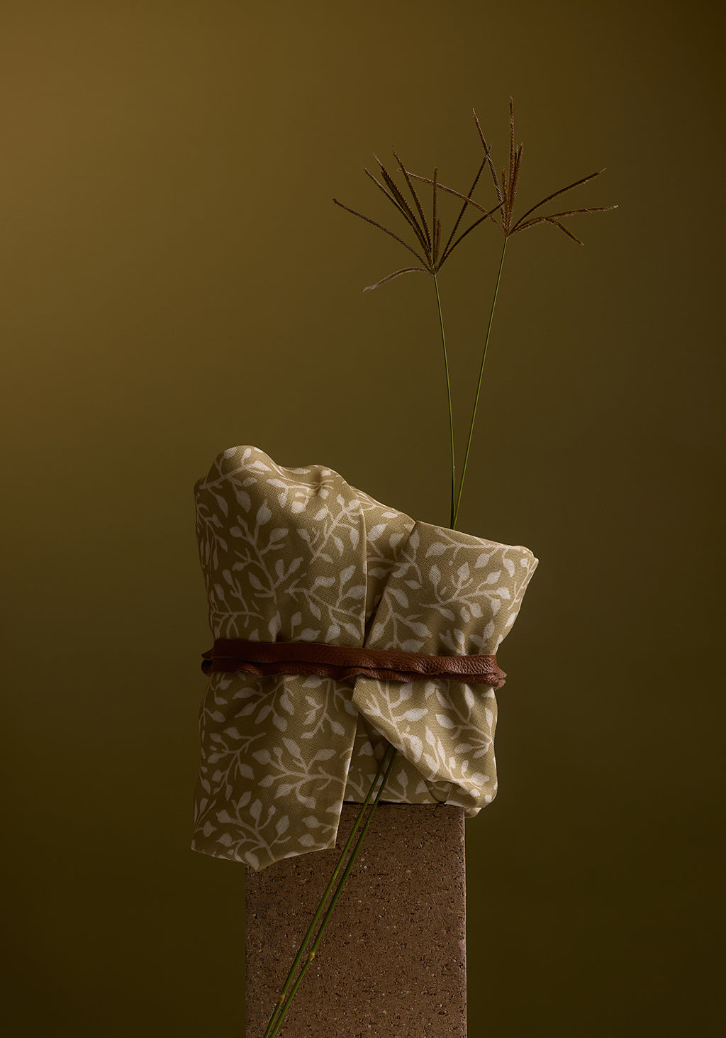 Folded fabric with a plant on a brown background