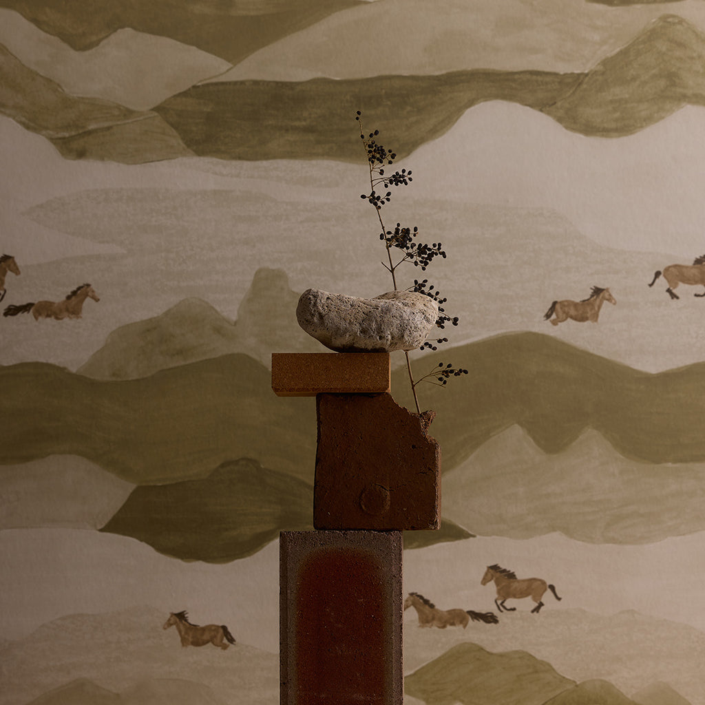 Decorative wall art with a mountain landscape and horses, featuring a central wooden sculpture.