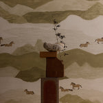 Decorative wall art with a mountain landscape and horses, featuring a central wooden sculpture.