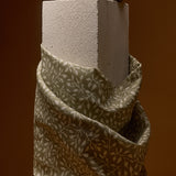 Textured block with a fabric-wrapped base on a brown background