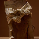 Wooden log with a checkered cloth tied around it against a brown background