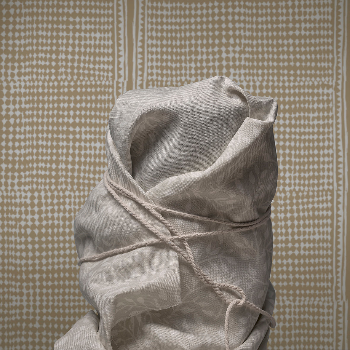 Tied sack made of fabric against a textured wall.