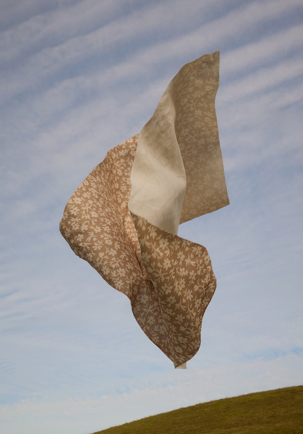 Floral fabric tossed in the air against a blue sky