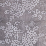 Detail of wallpaper in a minimalist floral print in light gray on a mottled gray field.