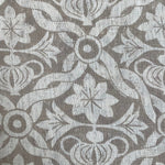 Close-up of fabric in a floral lattice print in white on a light brown field.