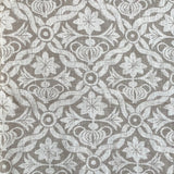 Detail of fabric in a floral lattice print in white on a light brown field.