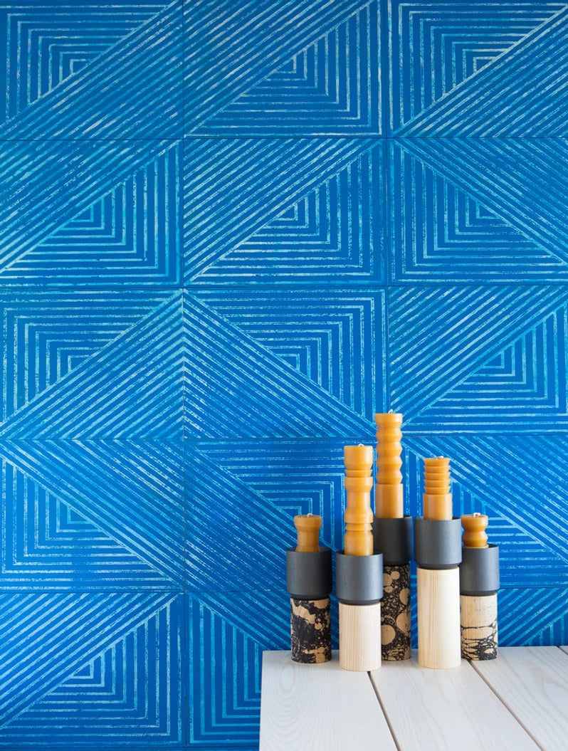 Installation of leather wall tiles in an angular geometric pattern in blue and white with a vignette of candlesticks in the foreground.