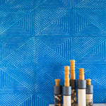 Installation of leather wall tiles in an angular geometric pattern in blue and white with a vignette of candlesticks in the foreground.