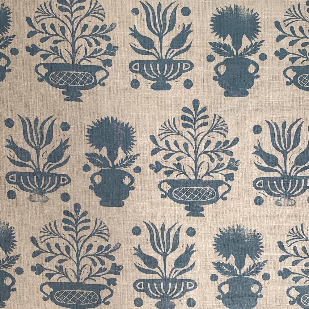 Detail of fabric in a repeating vase and plant print in blue on a cream field.