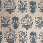 Detail of fabric in a repeating vase and plant print in blue on a cream field.