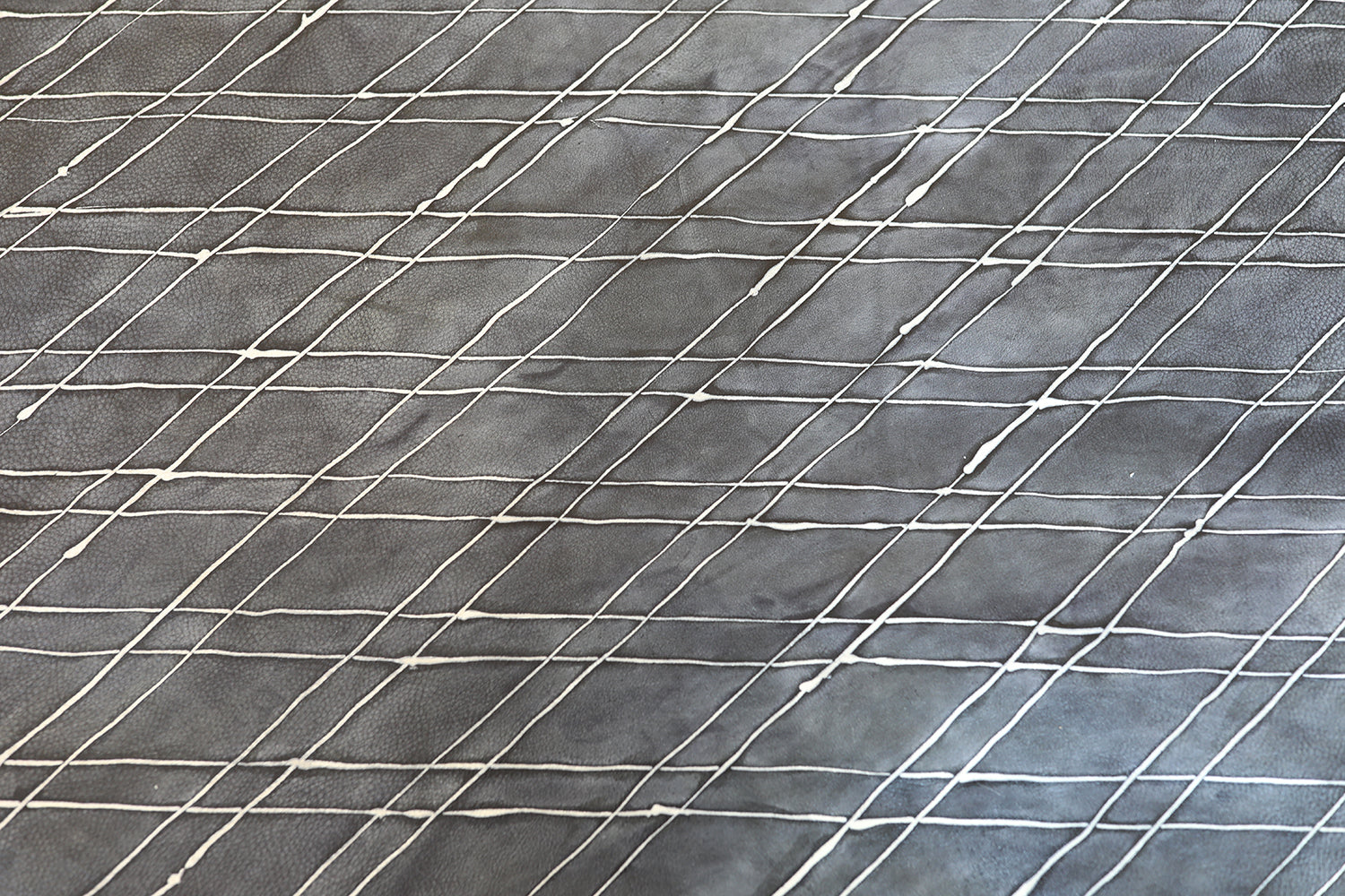 Close-up of a cowhide rug in gray with a white lattice overlay.