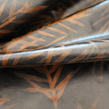 Detail of a draped cowhide rug in black with a brown botanical overlay.