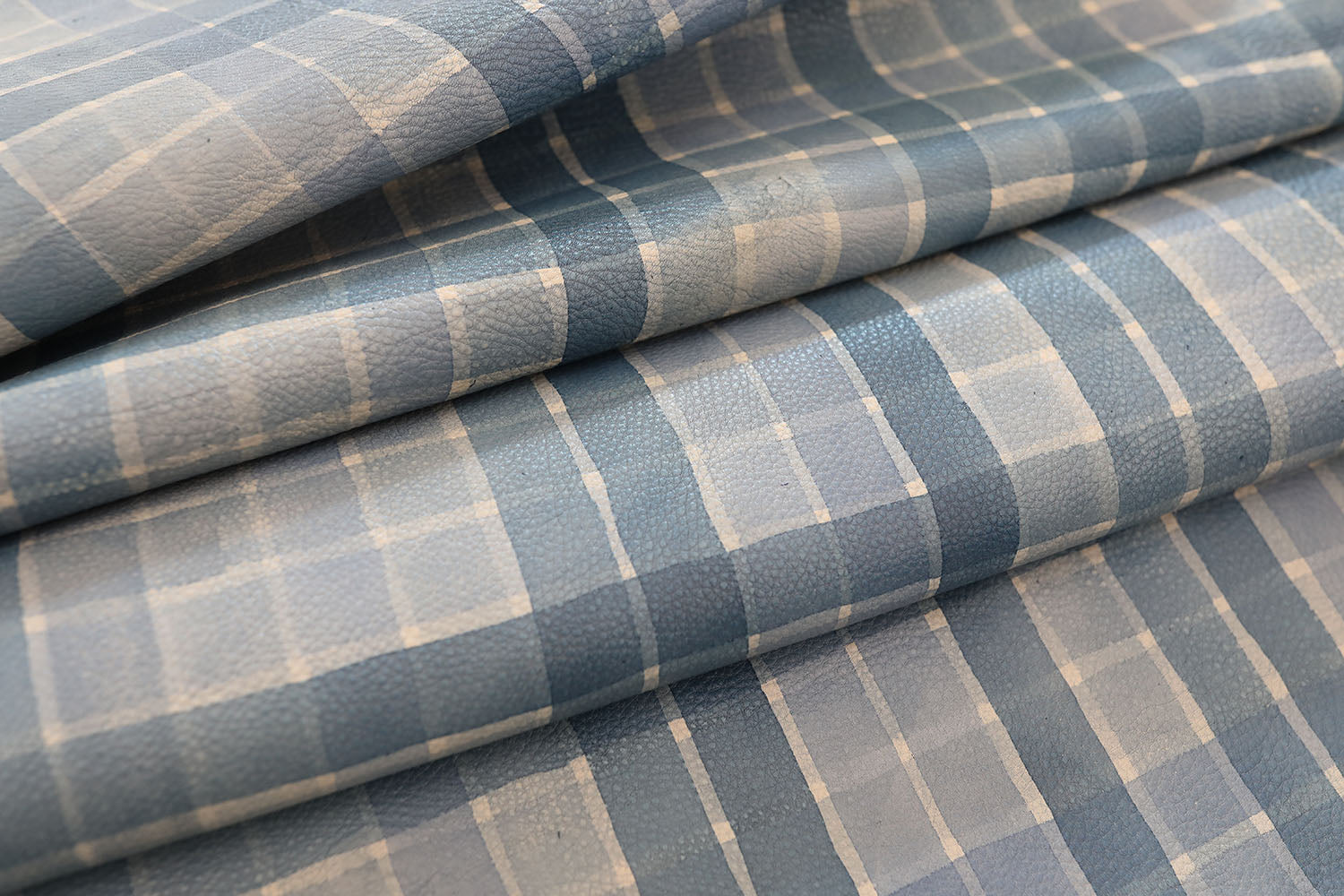 Detail of draped upholstery leather in a plaid pattern in shades of blue and cream.