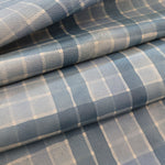 Detail of draped upholstery leather in a plaid pattern in shades of blue and cream.