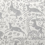 Detail of fabric in a deer, leaf and flower print in gray on a white field.