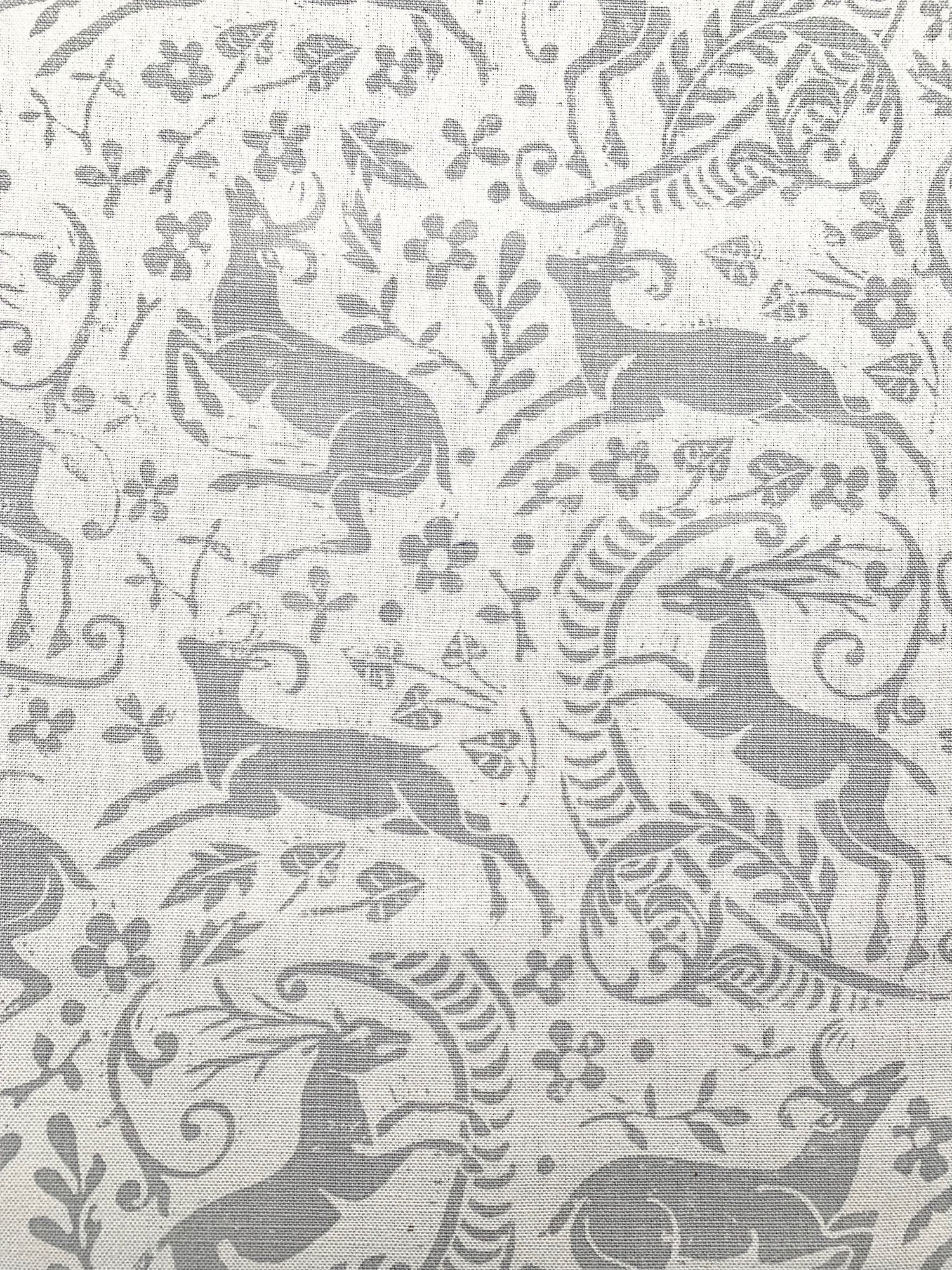 Detail of fabric in a deer, leaf and flower print in gray on a white field.