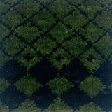 Close up for a handknotted rug in a black lattice design on a green field. 
