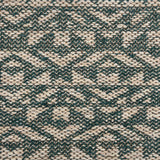 Handwoven rug detail in an angular geometric pattern in teal and beige.