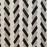 Detail of fabric in a geometric stripe print in black and tan on a white field.