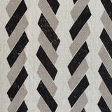 Detail of fabric in a geometric stripe print in black and tan on a white field.