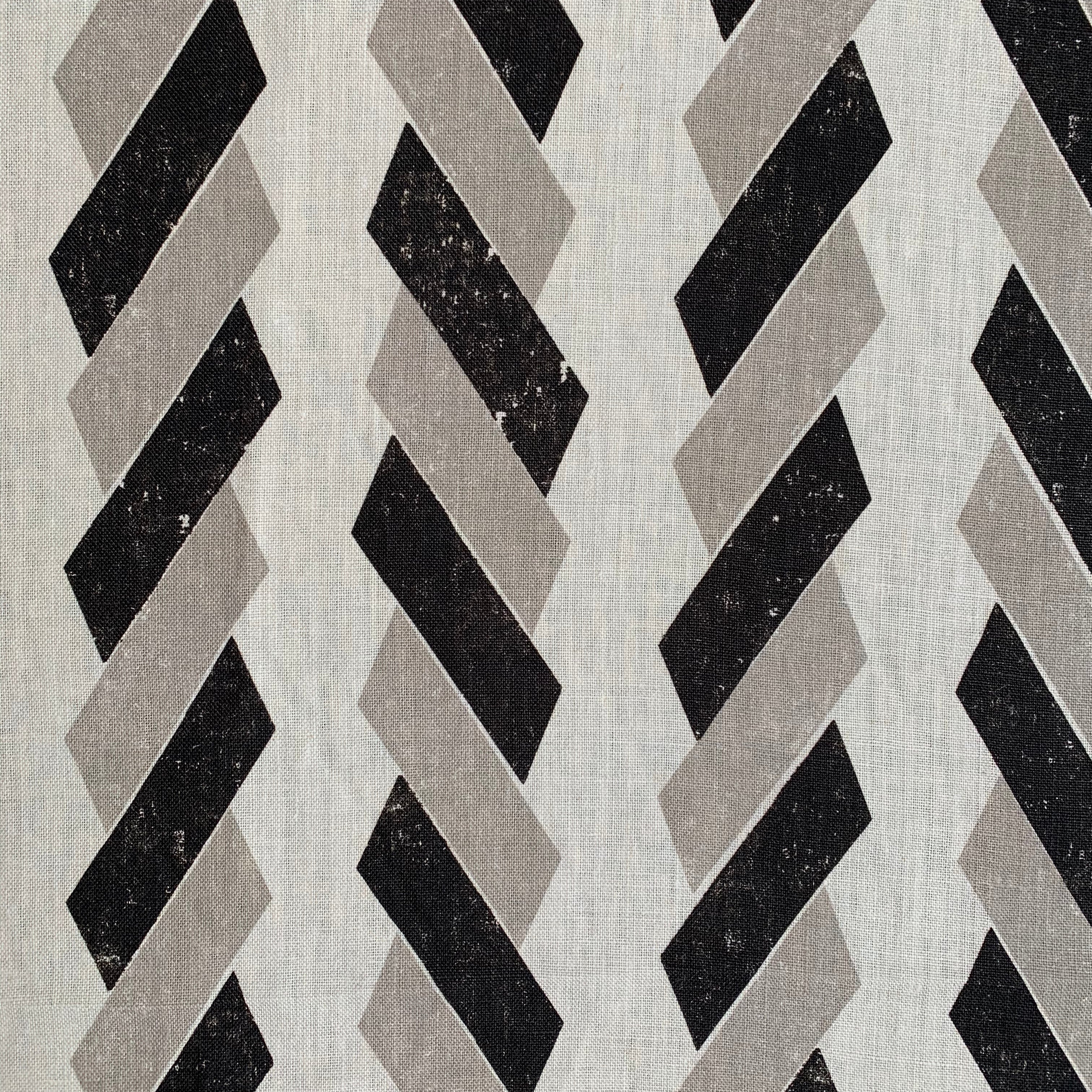 Detail of fabric in a geometric stripe print in black and tan on a white field.