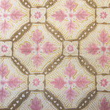 Detail of fabric in a painterly botanical grid in shades of pink, yellow and brown on a cream field.
