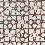 Detail of fabric in a botanical lattice print in brown on a cream field.