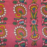 Detail of fabric in a dense floral stripe in pink, yellow and green on a pink field.